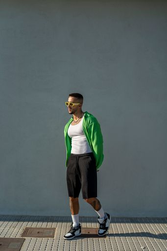 A vertical of a Spanish bearded attractive young male posing in stylish clothes on the street