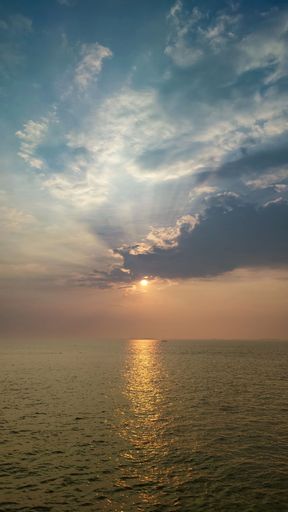 Sunset over the sea with sun rays breaking through clouds