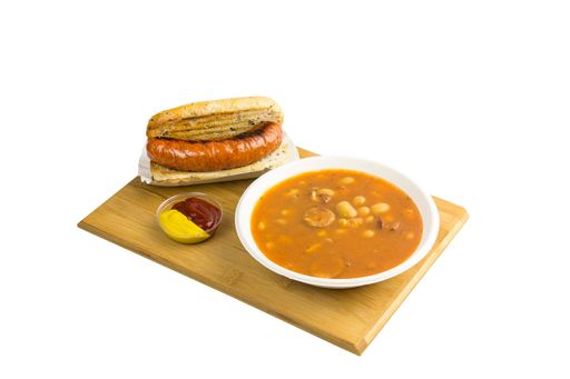 Bean soup and grilled sausage with ketchup and mustard on a cutting board isolated on white background