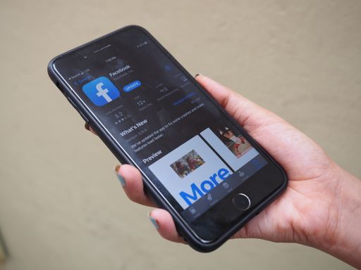 iPhone 7 plus jet black Color. Young Women with blue nail polish Open apps FACEBOOK application on the app store screen on rustic brown