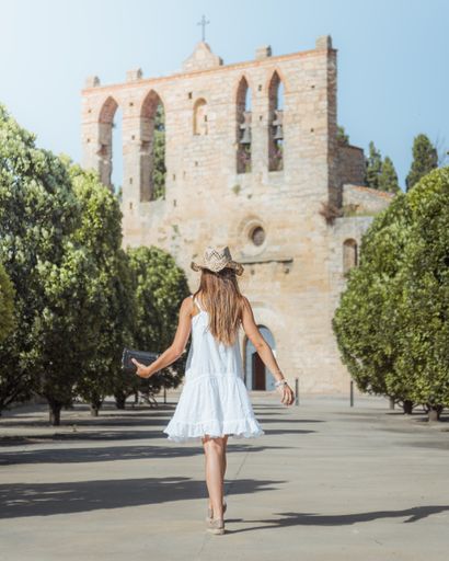 A lady with a hat walking towards a castle in summer
