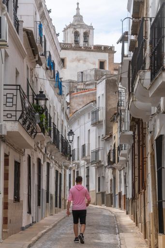 Young person in sportswear walking through the narrow medieval stone streets of alburquerque with balconies in their windows. Extremadura. Spain.