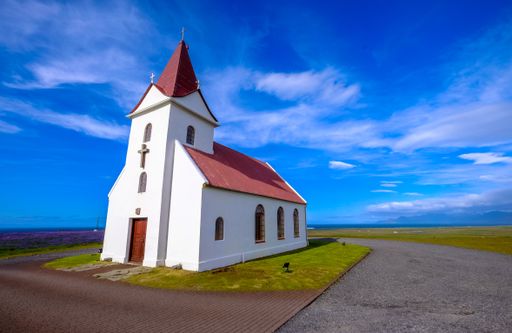 A wide shot of white Icelandic Lutheran Church  under a clear blue sky in Iceland