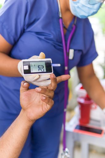 A doctor measuring patients blood glucose with a glucometer in a hospital