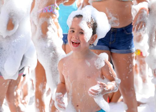 A cute little girl having fun at the foam party during a local party
