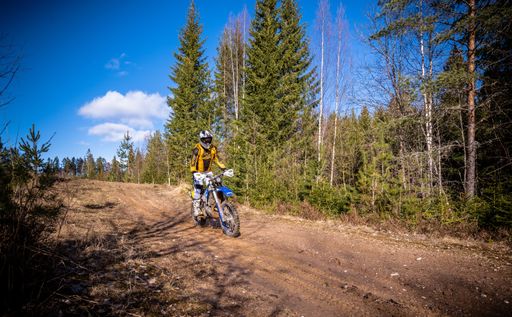The young man rides motocross on the track through the woods