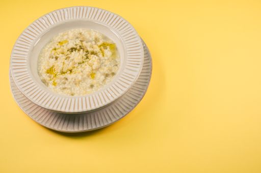 A plate of delicious porridge with corn and melted butter isolated on a yellow background with free space for text
