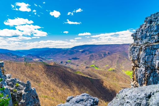 Scenic view of rocky cliffs and rolling hills under a vibrant blue sky in West Virginia.