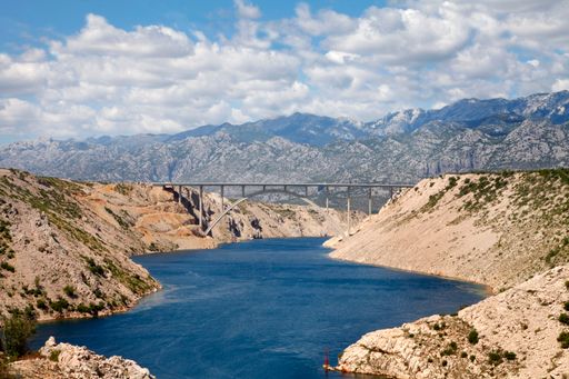 An idyllic landscape of a tranquil river winding through a mountainous area under a bridge in Croatia