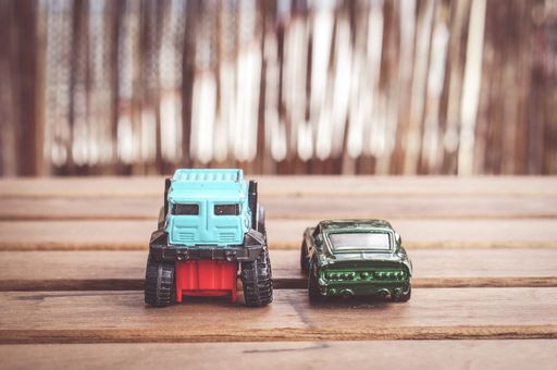 Two Mattel Hot Wheels toy cars on a wooden table