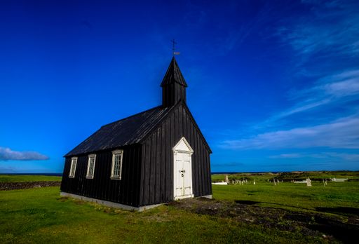 A church in the middle of a grassy field under a clear blue sky at daytime