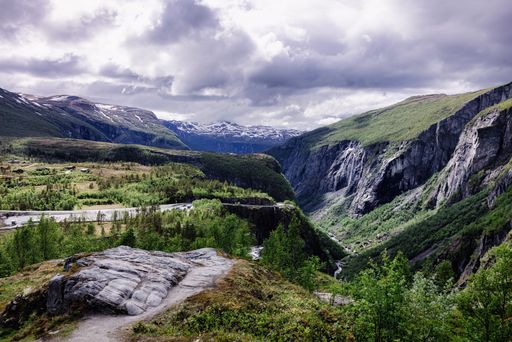 Majestic Norwegian mountain landscape with lush greenery and dramatic cliffs under a cloudy sky.