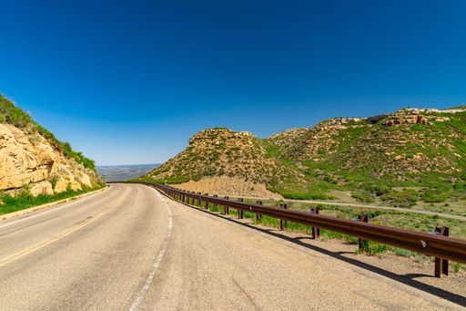 Scenic highway through rocky hills under a clear blue sky, perfect for travel and adventure themes.