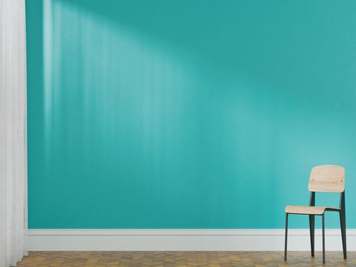 Minimalist interior with a single wooden chair against a turquoise wall and parquet floor, sunlight streaming in from a window.