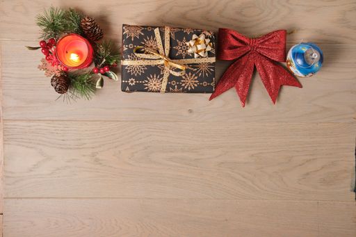 A candle and the Christmas tree toys on a wooden surface viewed from above