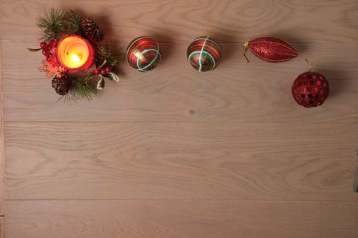 A candle and the Christmas tree toys on a wooden surface viewed from above