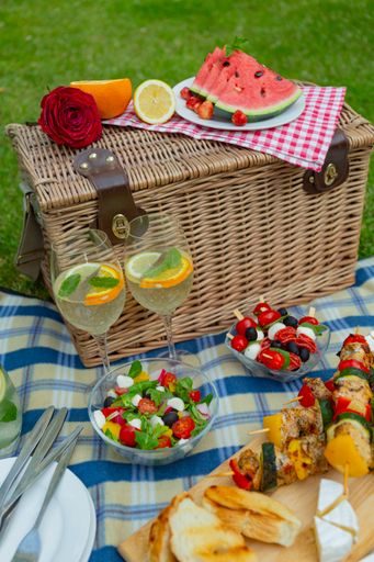 A vertical shot of tasty food on a plaid blanket for a picnic