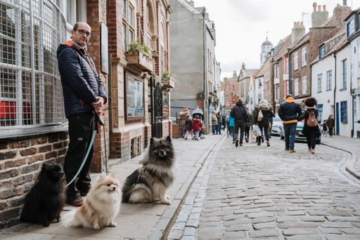 A man with his dogs on the street at the seaside town of Whitby in the United Kingdom