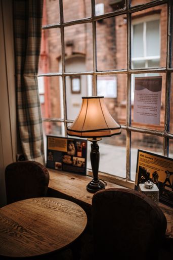 A shot of a cozy cafe interior and a table lamp near the window with brick walls in the background in the town of Whitby, United Kingdom