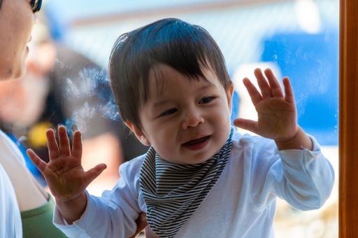 A closeup shot of an Asian kid behind a window