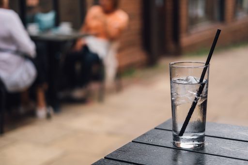 A shot of a glass of pure, refreshing water with ice on the table with a blurred background of cafe