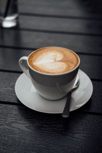 A vertical closeup shot of a cup of cappuccino decorated with heart