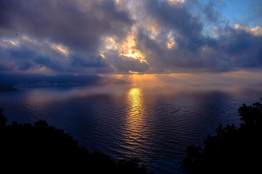 A beautiful shot of the sea reflecting the sunlight under a cloudy sky