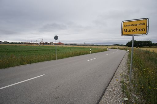 A yellow sign beside an empty road in the countryside in Munich, Germany under a gray cloudy sky on a gloomy day