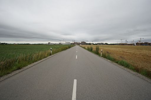 An empty road stretching into the horizon under a gloomy sky in the German countryside in Munich