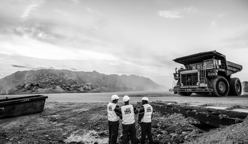 A rear view of three men looking at a Large Dump Truck transporting Platinum ore in South Africa