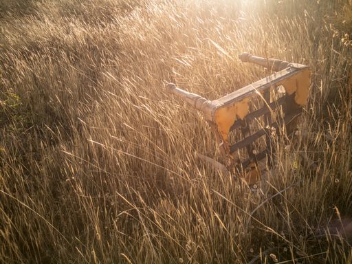 A closeup view of an abandoned yellow wooden table in the middle of a field on a sunny day