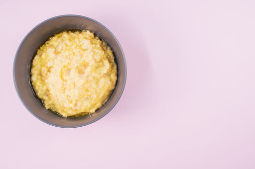 A top view of scrambled omelette on a bowl isolated on light purple background