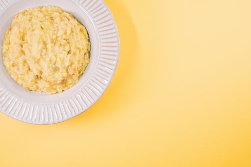 A top view of scrambled omelette on a paper plate isolated on an orange background