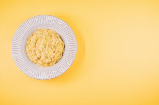 A top view of scrambled omelette on a paper plate isolated on yellow background