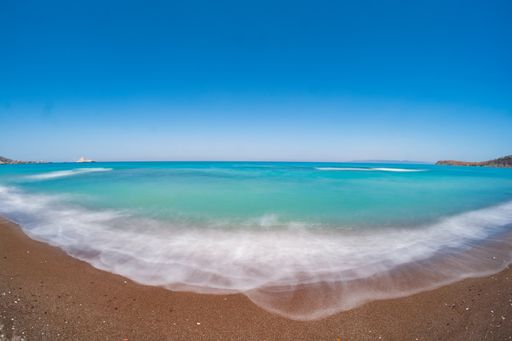 A scenic view of a beautiful beach under a clear blue sky at summertime with long exposure