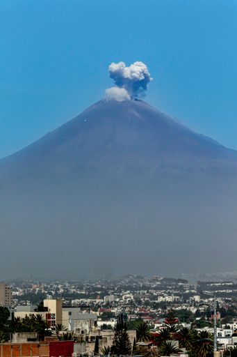 A vertical shot of Popocatepetl volcano with cityscape during the eruption