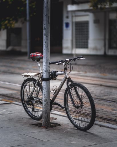 A vertical shot of a bicycle tied to a pole outdoors during daylight