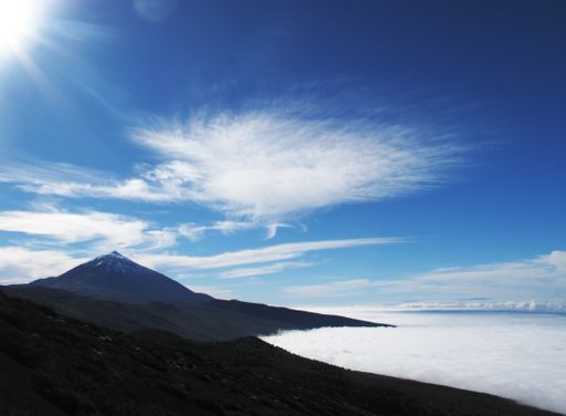A beautiful shot of mountains above the fog under a blue sky at daytime