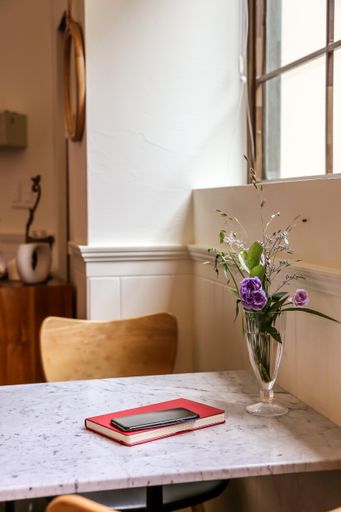 A vertical shot of a notepad and a phone on the table decorated with flowers in an old cafe