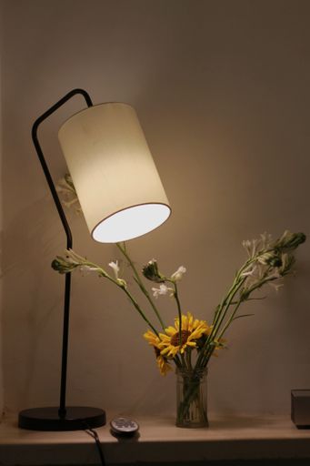 A vertical shot of a lampshade and sunflowers in a glass vase