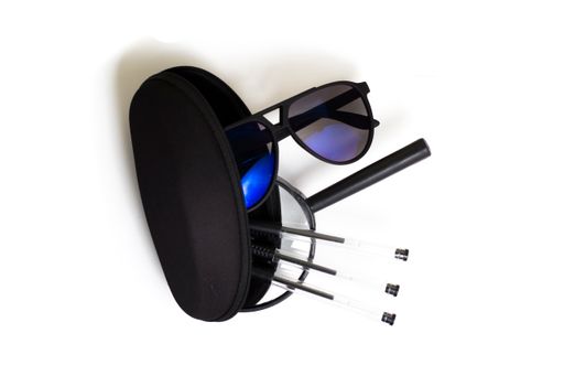 A sunglass, magnifier and pens on a white surface viewed from above