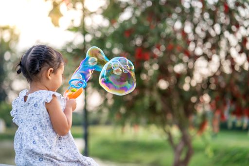A cute little Thai girl playing with soap bubbles in a park