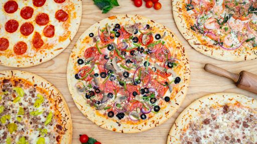 A high angle closeup shot of different pizzas on a wooden surface - perfect for a restaurant poster