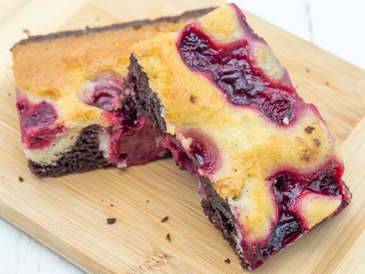 Close-up of two cherry chocolate brownies on a wooden board, showcasing the vibrant red cherries and rich chocolate layers.