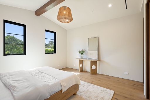 Modern minimalist bedroom with natural light, wooden flooring, and elegant decor.