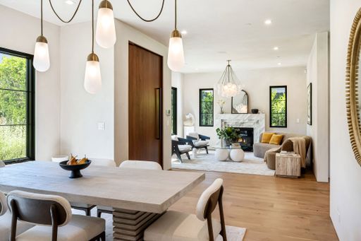 Modern open-plan living and dining area with stylish decor, wooden floors, and large windows offering natural light.