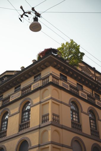 Historic building with ochre facade, arched windows, and rooftop garden