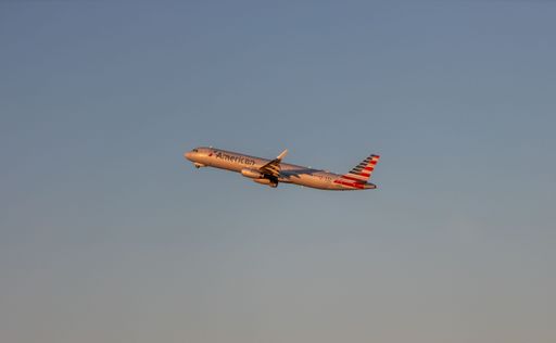 An American Airlines plane takes off in Boston during a sunset sky.