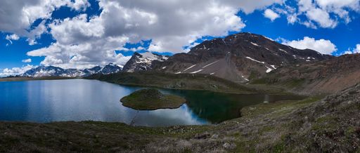 A vertical shot of a view of mountains and a blue sky with the clear lake from natural reservation Gran Paradiso, Italy