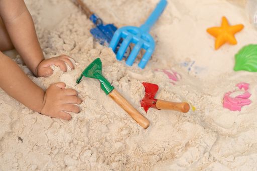 A top view of a child playing with beach toys on the sand